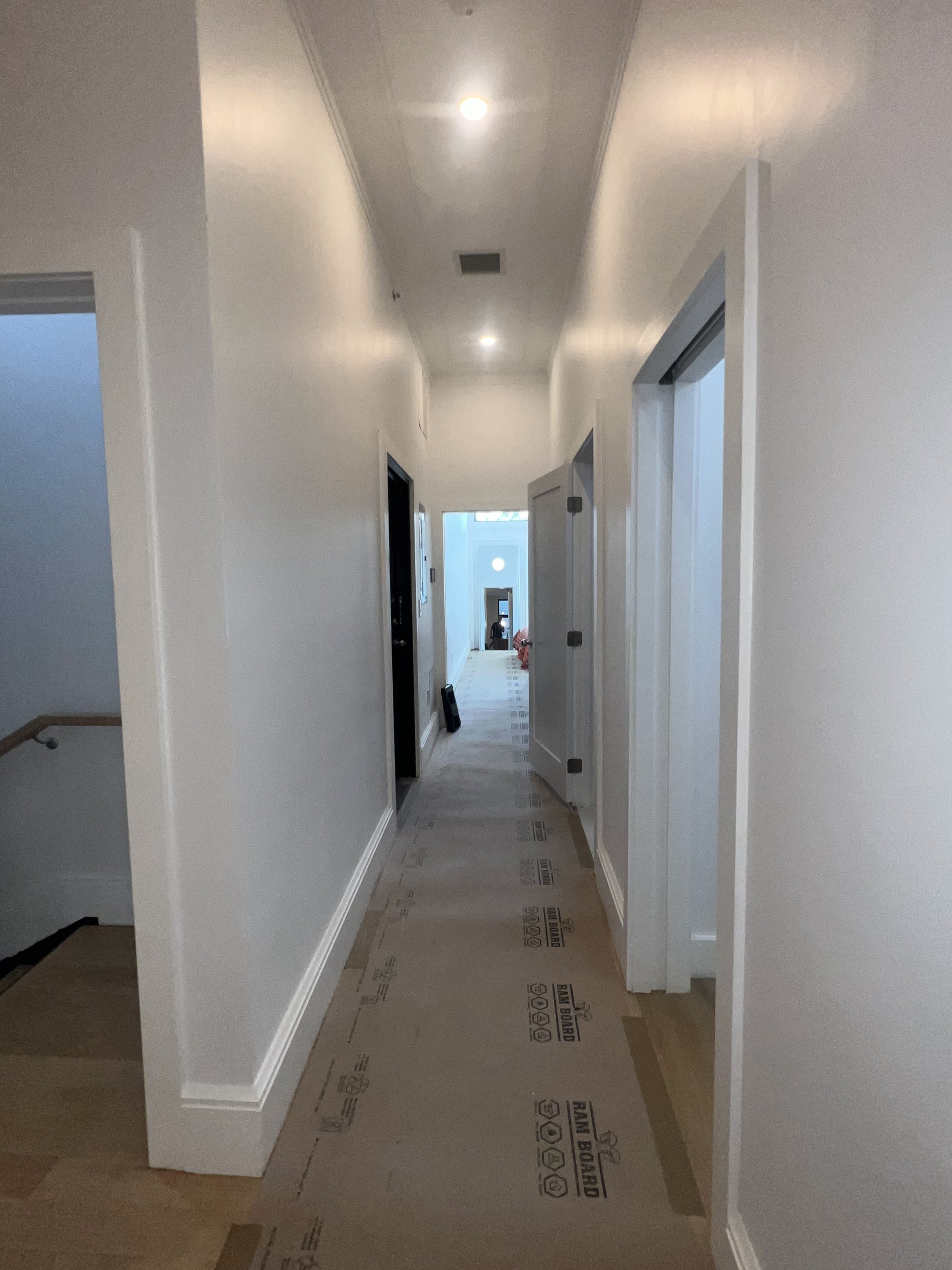 Hallway mid-project with floor protection down and trim being fitted